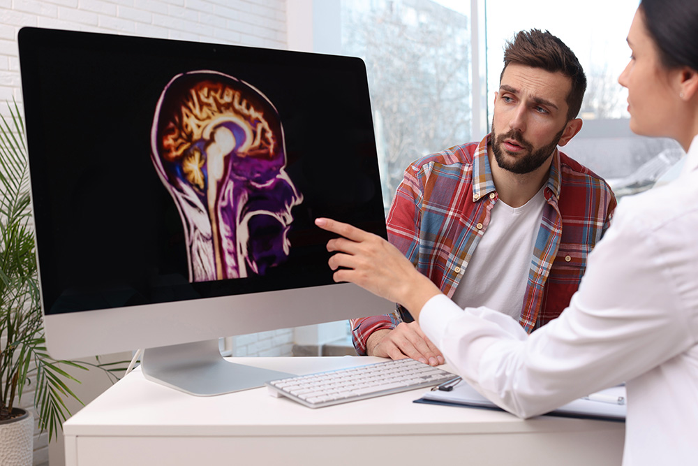 Doctor and patient discuss brain tumor genetics in office.