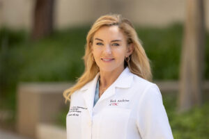 A portrait of Dr. Joni Doherty standing outside in a white medical coat.