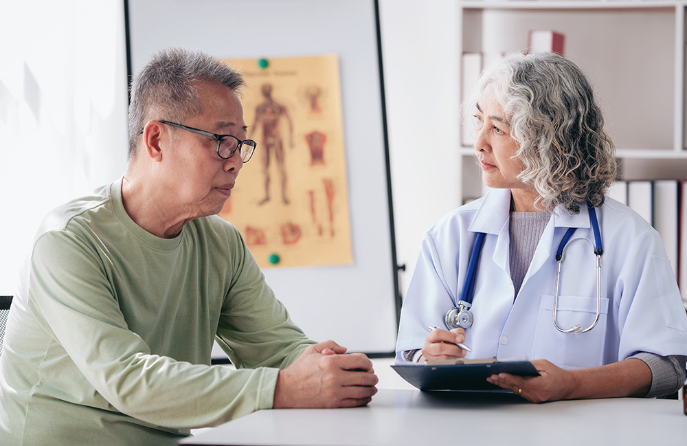 Female doctor listening symptom of senior patient and taking notes information on clipboard to writing.